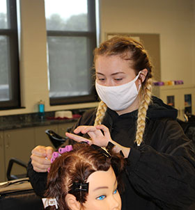 Student doing hair style on mannequin 